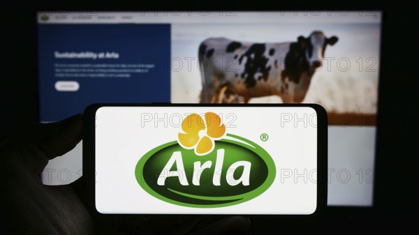 Stuttgart, Germany, 09-08-2023: Person holding mobile phone with logo of Nordic dairy company Arla