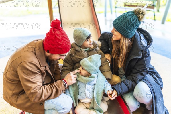 Parents and children enjoying quality time together on a slide at the playground, embracing the joy