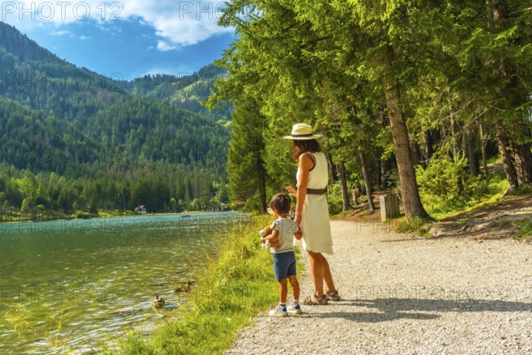 Tourists enjoying the scenic landscape of lake dobbiaco, surrounded by the majestic dolomites,