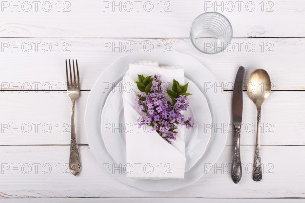 Spring festive table setting with vintage cutlery and lilac flowers on white wooden table, copy