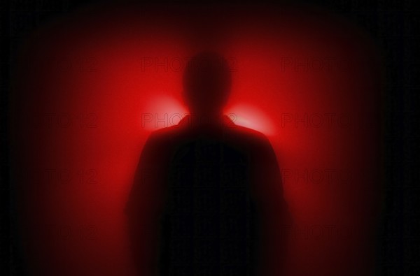 A diffuse figure in the red backlight, concept image, fear, anonymity, AI generated