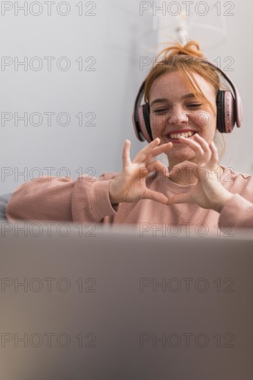 Smiley female teacher showing heart sign students during online class
