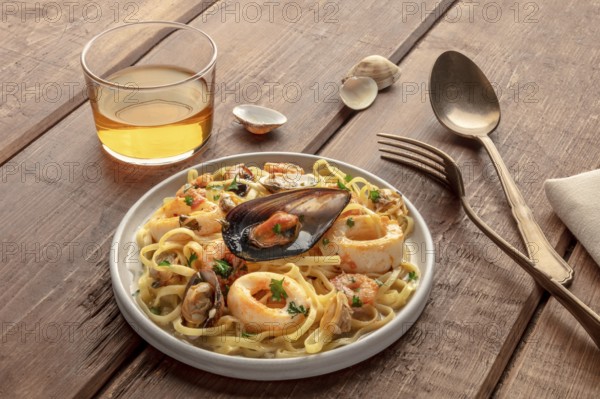 Seafood pasta. Tagliolini with mussels, shrimps, clams and squid rings, with a glass of wine on a