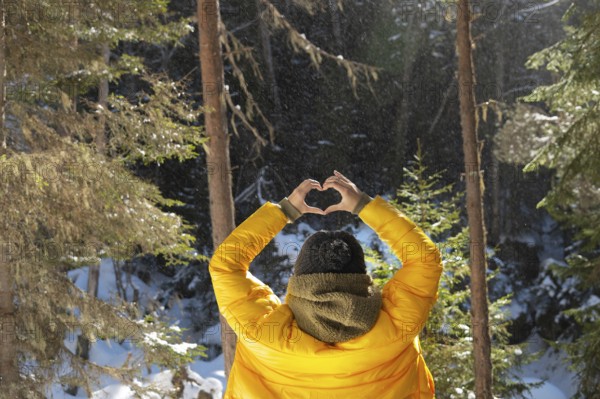 Back portrait young caucasian woman and shows fingers gesture of heart, love at eye level. Back