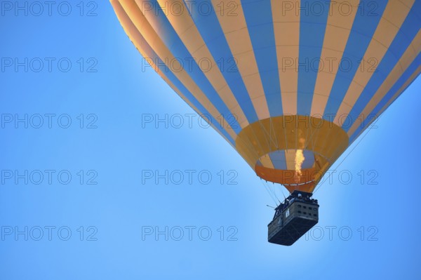 Flying hot air balloon against bright blue sky