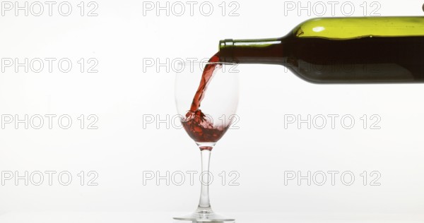 Red Wine being poured into Glass, against White Background