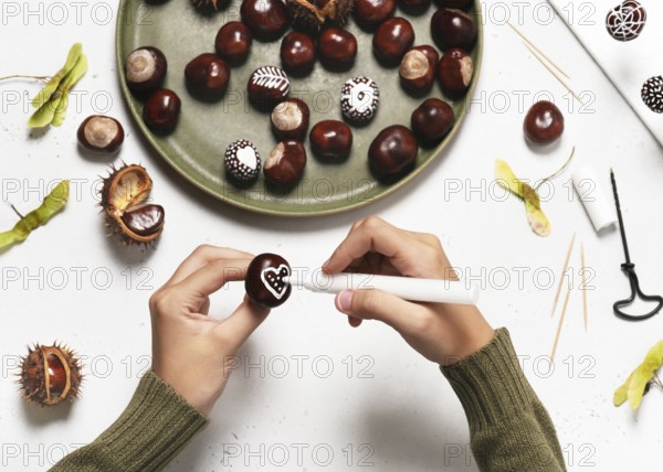 Step 3: Draw a heart on a chestnut with a white acrylic pen. Handicrafts with children. Step by