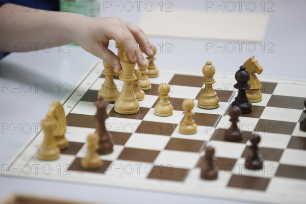 Child plays chess and moves a piece, focus on the action