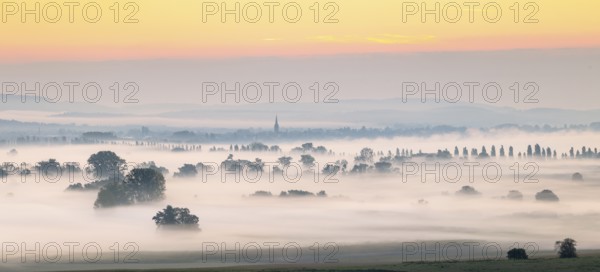 A misty landscape at sunrise with distant trees and cathedral tower, Galgenberg, Aachried,