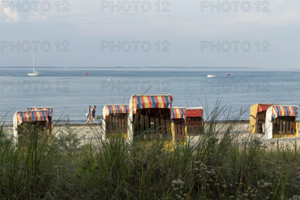 Symbolic picture weather, summer, bathers and beach chairs in the evening light on the sandy beach