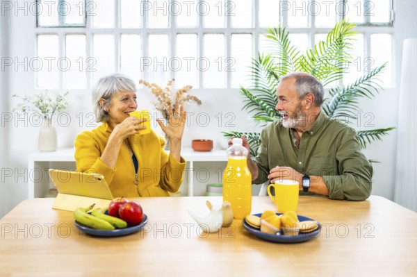 Frontal view of a happy caucasian mature couple talking while eating healthy breakfast at home