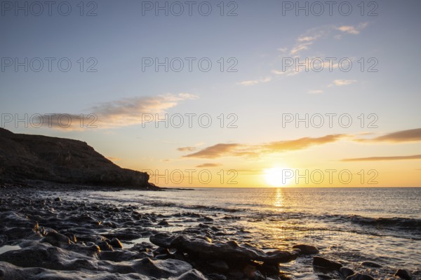 View of the sunrise over the Atlantic. View over a stone beach on a volcanic island. Cold lava