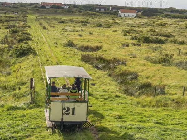 Horse-drawn railway runs through a wide green landscape with scattered houses, spiekeroog, east