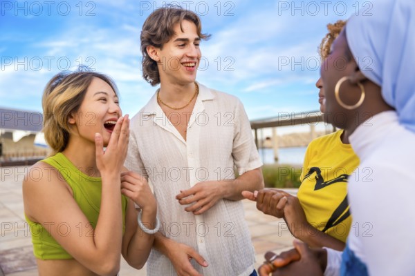 Close-up photo of multi-ethnic group chatting an laughing outdoors in an urban space