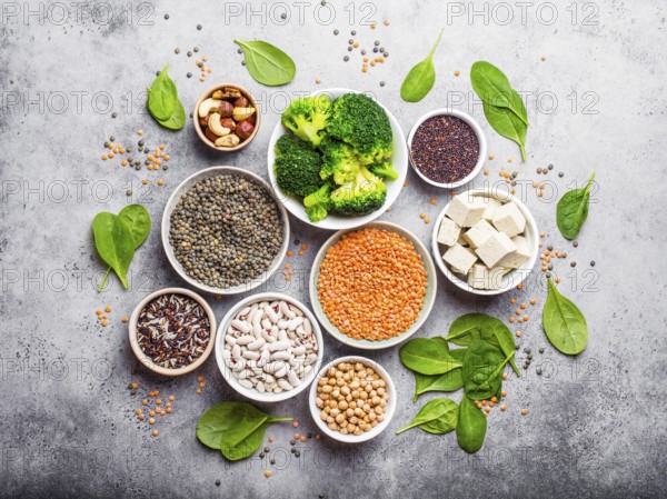 Top view of different vegan protein sources: beans, lentils, quinoa, tofu, vegetables, spinach,