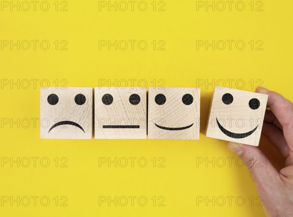 directly above view of smiley feedback icons on wooden blocks against yellow background