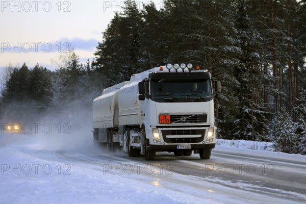 Volvo FH tanker truck transports gasoline, ADR 33-1203, on snowy highway on a winter afternoon.