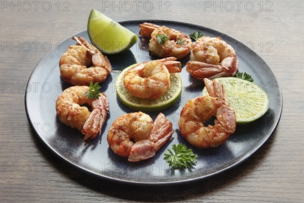 Shrimps with limes and parsley. Grilled shrimp on a rustic table. Spicy seafood appetizer