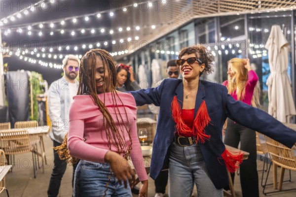 Happy multi-ethnic women dancing together at the terrace of a night bar