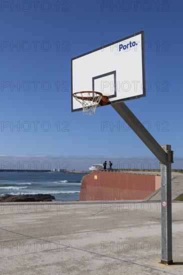 Basketball hoop in front of a blue sky with Porto lettering on the beach promenade in Matosinhos,