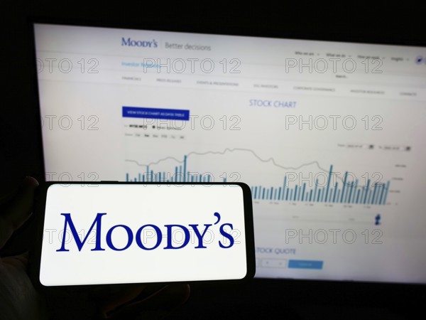 Stuttgart, Germany, 10-09-2022: Person holding mobile phnoe with logo of rating company Moody's