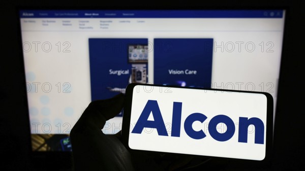 Stuttgart, Germany, 08-28-2022: Person holding cellphone with logo of eye care company Alcon AG on