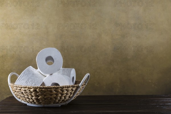 Rolls of toilet paper in the basket on the wooden background