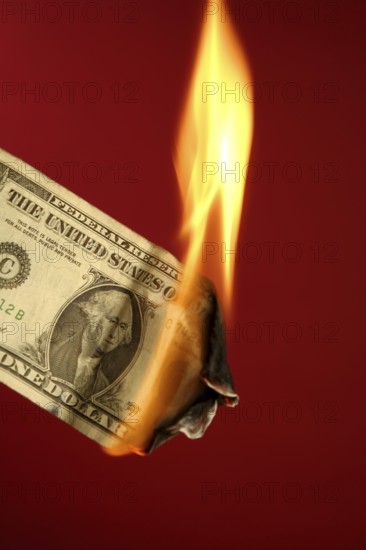 Dollar note, american currency burning in fire over red background, studio shot