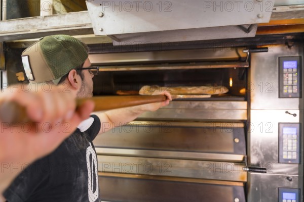 Baker of bakery in the workshop artisan workshop baking loaves in the oven