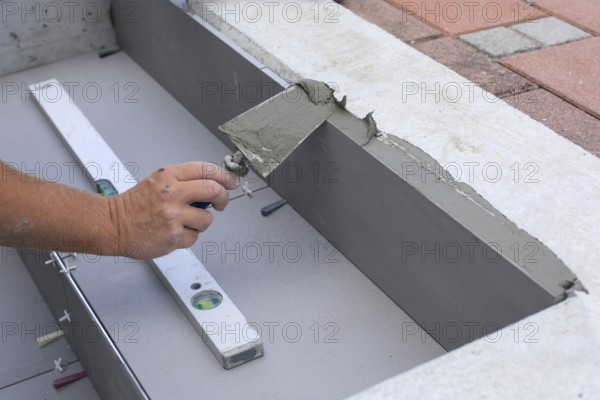 Tiler hands working on a new house entrance, local and professional handyman applying tiles to the