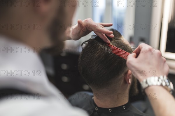 Faceless barber combing hair man before cutting