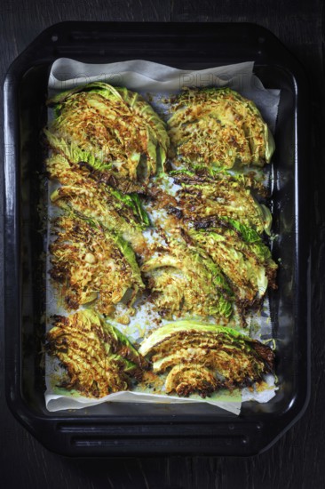 Baked savoy cabbage with parmesan cheese, honey and spices on baking sheet