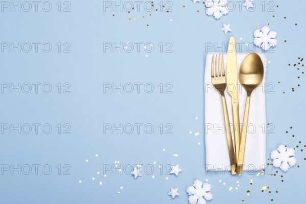 Christmas or new year table setting with golden cutlery on the blue background with copy space