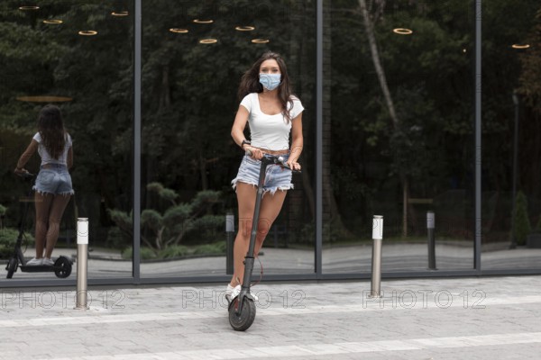Woman with mask riding electric scooter