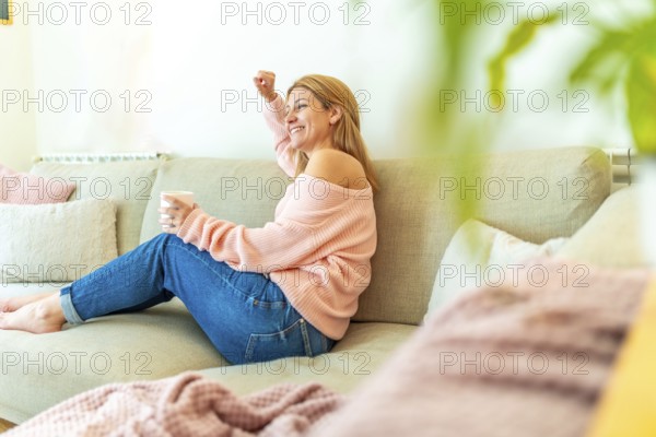 Horizontal photo full length and copy space of a blonde casual adult woman celebrating raising fist