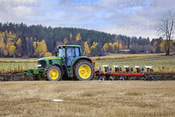 Farmer ploughing stubble field with John Deere 7530 tractor and plough on a day of autumn. Salo,