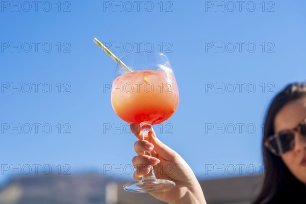 Woman raising a cocktail glass with sex on the beach cocktail in a rooftop