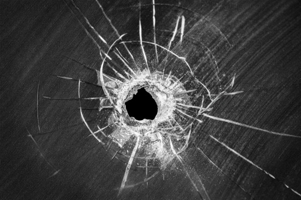 Bullet shot cracked hole on car windshield or accident damaged broken house window glass