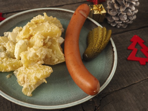 Tasty homemade potato salad with organic sausage and gherkin, traditional Christmas meal