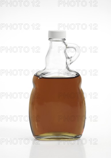 BOTTLE OF MAPLE SYRUP AGAINST WHITE BACKGROUND