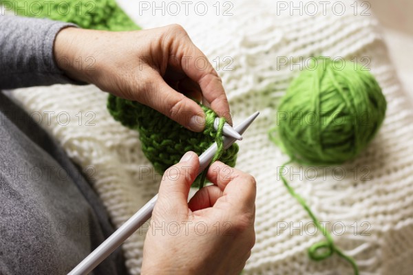 High view person knitting with green thread