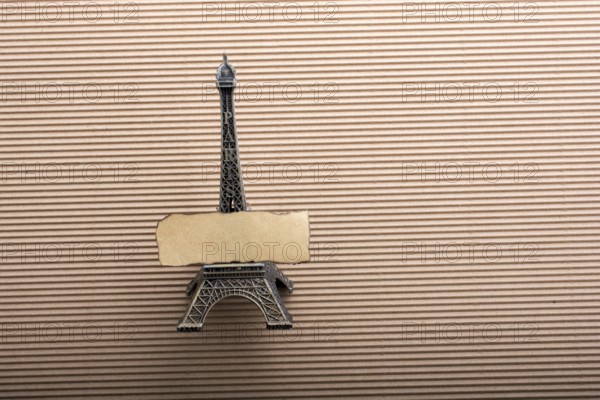 Burnt piece of paper on model Eiffel tower on cardboard
