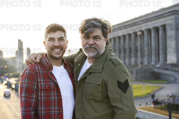 Hispanic gay couple hugging while looking at the camera in Buenos Aires city