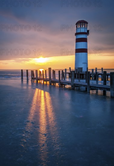 Winter landscape with lighthouse on a lake at sunset