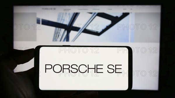 Stuttgart, Germany, 08-20-2023: Person holding cellphone with logo of German company Porsche