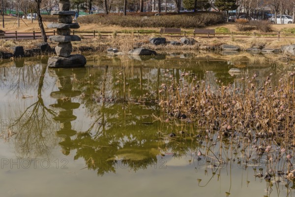 Stone tower in small pond in city park on sunny winter day in South Korea