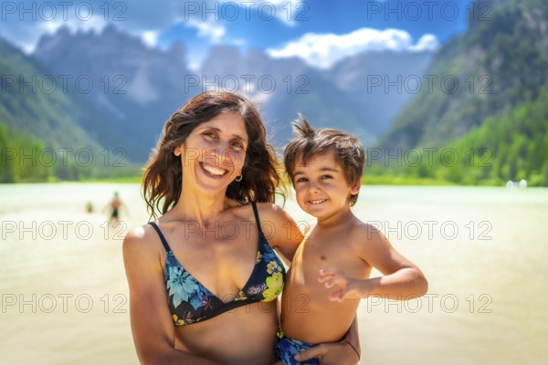 Mother and son smiling and enjoying summer vacation while swimming in the scenic lago di landro in