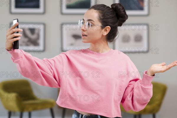 Blogger with glasses recording herself with phone