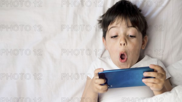 Flat lay kid with phone bed