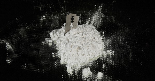 Powder Drug Falling on Razor Blade and Syringes against Black Background